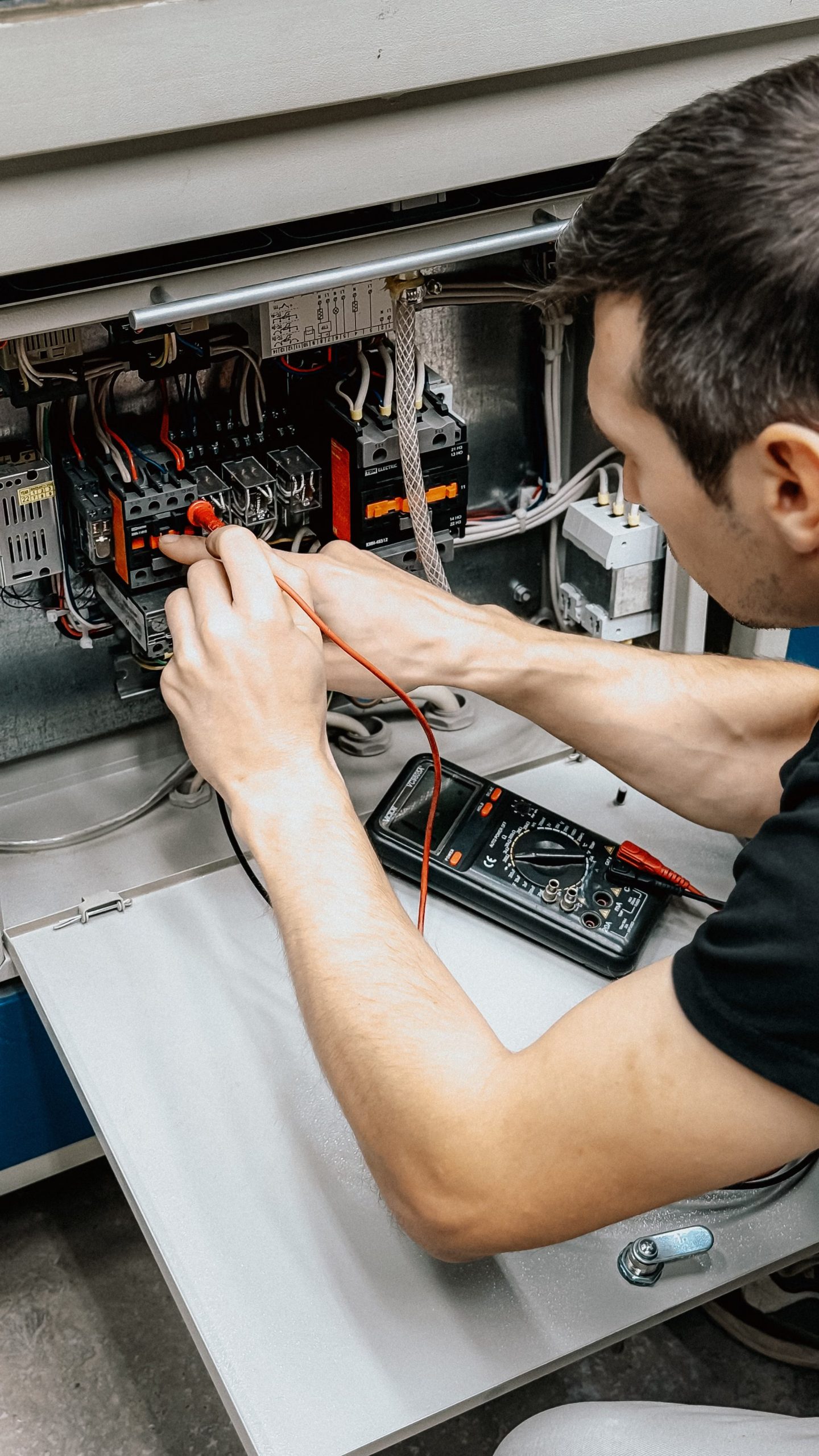 Technician testing wiring in an electrical control panel with a multimeter